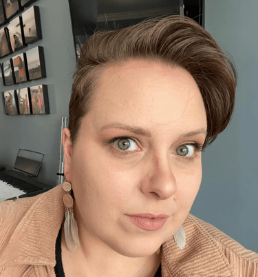 Head and shoulders of Wendy, a white woman with short brown hair, in front of a blue wall