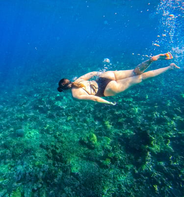 a woman in a bikini top swimming in the ocean