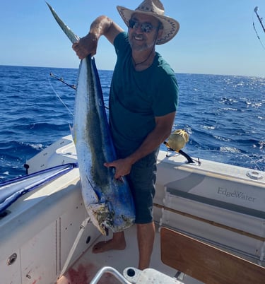 Un client souriant tenant une dorade coryphène dans les mains