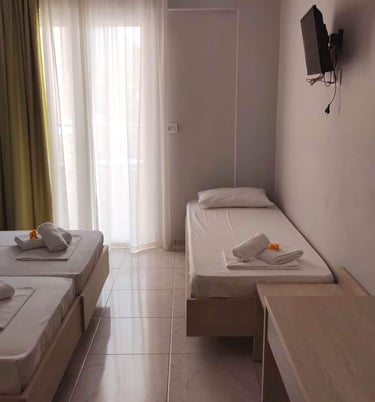 a triple bedroom with three beds and a television