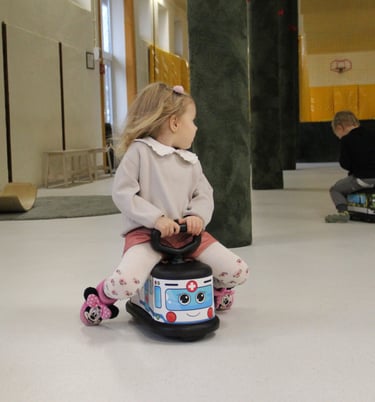 mergaitė važiuoja ir žaidžia greitosios pagalbos paspiriama mašinėlė, kuri skatina vaidmenų žaidimą