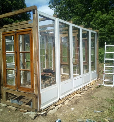 a greenhouse with a ladder to the side of it