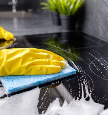 Cleaner cleaning a counter top with yellow gloves and a blue sponge