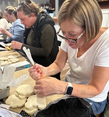 a woman in glasses and a white shirt is decorating sugar cookie