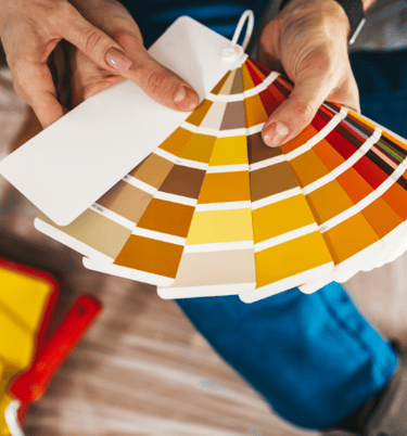 a person holding a color palette and a paintbrush