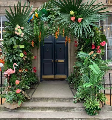 a doorway with a large arch decorated with tropical plants