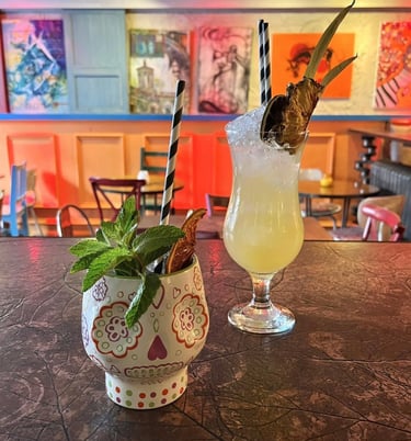 a couple of styled cocktail drinks in fancy glasses with mint leaves