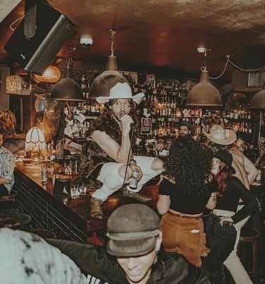 a man in a hat singing on top of a crowded bar