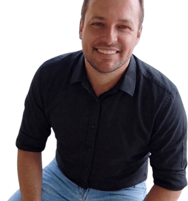 A smiling man wearing a black button-down shirt, blue jeans, and sunglasses on his head.