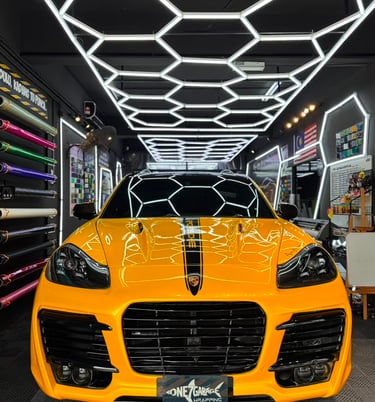 Porsche Cayenne wrapped in gloss yellow with black racing stripe