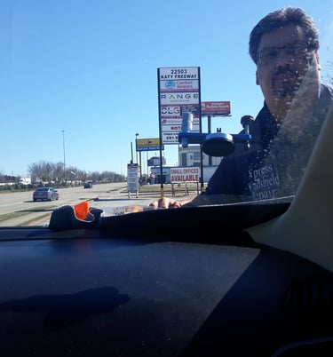 a man in a black shirt is driving a car
