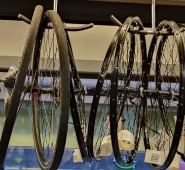 a bunch of bike wheels hanging from a rack in turku pyörähuolto