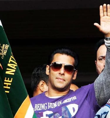a man in a purple shirt and sunglasses is waving his hand