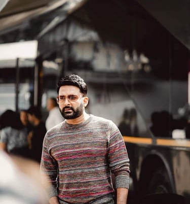 a man in a striped sweater and jeans standing in front of a food truck