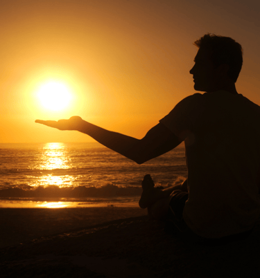 a man sitting on a beach holding a frisbee