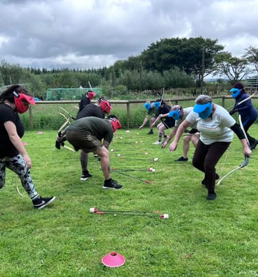 a group of people playing archery tag on a grassy field