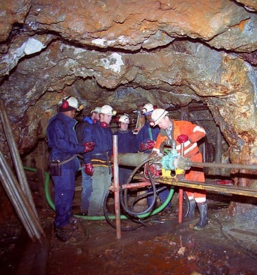 A group of people in a cave like area with old mining machinery
