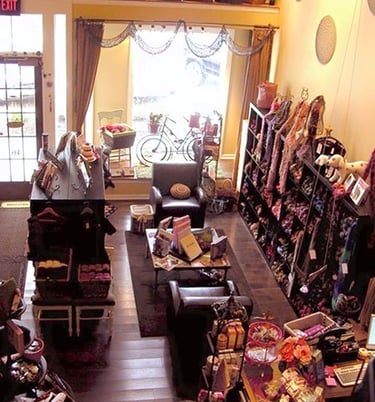 Cozy knitting shop interior with shelves of colorful yarn skeins, seating area, and boutique craft supplies.