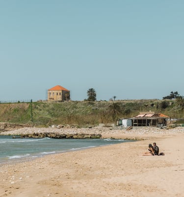 A couple sits on a sandy Mediterranean beach in Jbeil, Lebanon by Lebanese photographer Emma Jowdy