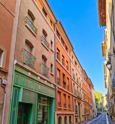 viale di piccola cittadina francese costeggiata da palazzine colorate tipiche della provenza