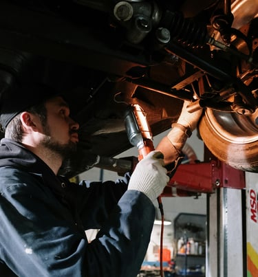 Mécanicien réalisant un diagnostic automobile sous un véhicule en atelier