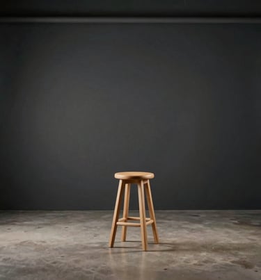 A wide shot of a minimalist photography studio in Buffalo, NY, dark charcoal walls, simple wooden stool, soft off-white lighting equipment, North American / US industrial aesthetic.