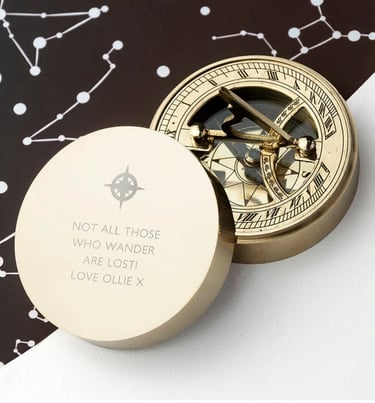 a gold compass  with a quote on it