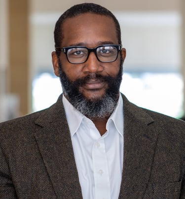 A picture of Dr. Leonard Bright with a beard and glasses on a white background