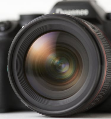 Close up of a camera lens reflecting a sun-drenched landscape, evoking the artist's perspective and warm cinematic style.