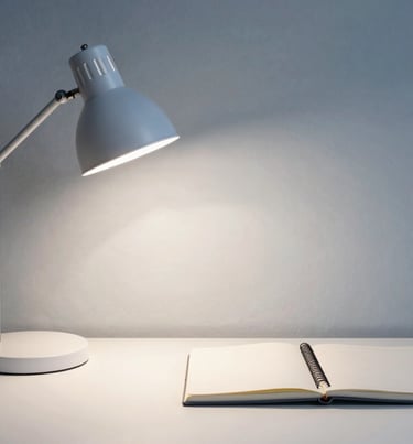 A portrait of a minimalist workspace with a single lamp and a notebook. Sophisticated muted blue and soft white colors, professional and calm mood, Northern European style.