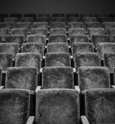 A minimalist black and white photograph of an empty auditorium with rows of velvet seats, conveying a refined and quiet North American artistic atmosphere.