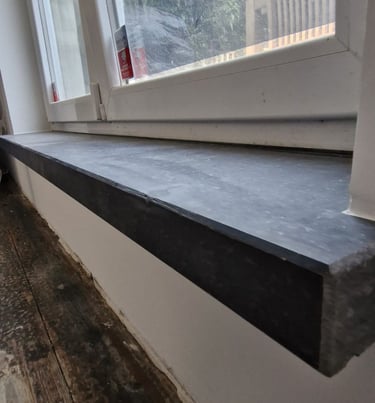 Pose sur mesure d’un appui de fenêtre en pierre bleue dans un logement en rénovation