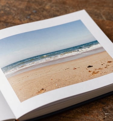A high-quality lifestyle photograph of a printed photo album laying open on a rustic wooden table, Soft Sand and Deep Brown color palette.