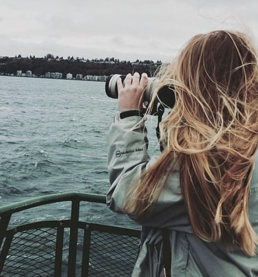 a woman taking a picture of a boat in the water