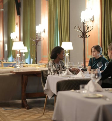 Three women enjoying a fine dining experience and wine at a luxury hotel restaurant lounge.
