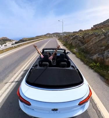 a man driving a convertible car down a road