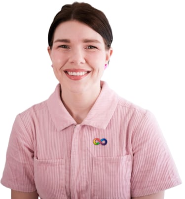 A photo of Frances, Occupational Therapist smiling and wearing a pink jumpsuit & neurodiversity pin