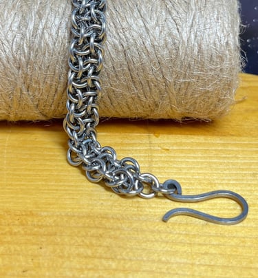 Photo of a chainmaille bracelet made of stainless steel draped over a bundle of jute twine