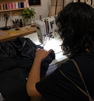 Mujer cosiendo a máquina en taller de costura de la tienda viento luminiscente de ropa artesanal boho, bohemio hippie