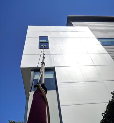 Cleaning a window on a second story commercial building with a five stage filtration water pool