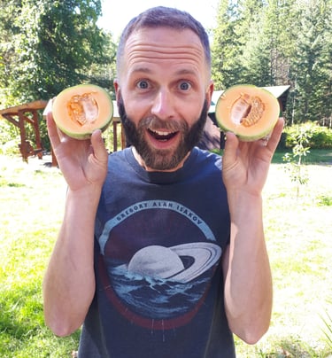 A portrait of the grower, Gavin Smith, holding two halves of a muskmelon