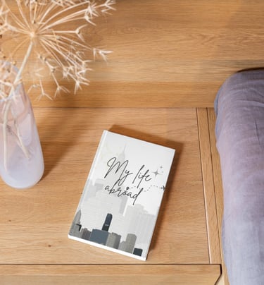 My Life Abroad travel journal on a wooden nightstand next to a dried flower arrangement.
