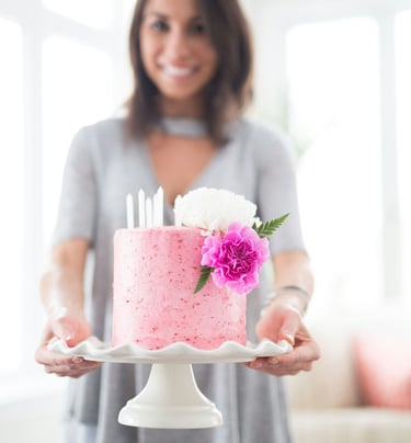 a woman holding a cake with candles and flowers.Tourism Consulting in England, Spain, Hungary