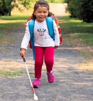 Child with strabismus walking with a O&M white cane for the legally blind and visually impaired with low vision