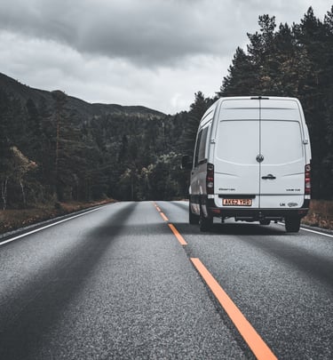 photo of camper van driving through forest in Norway