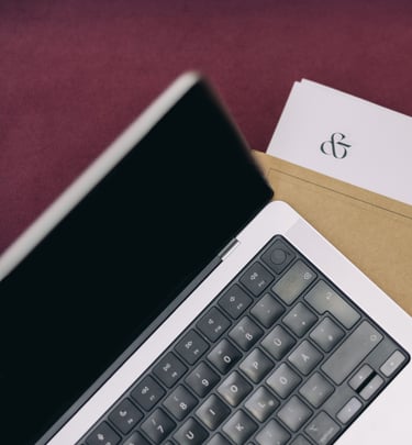 An open laptop on top of paperowrk on a desk.