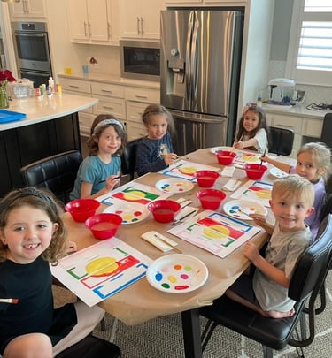 Kids smiling while painting at a table