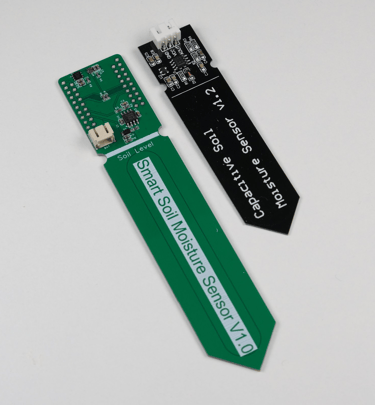 Our green PCB for complete plant monitoring next to a basic capacitive soil moisture sensor