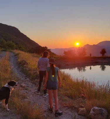 people walking down a path and looking at the beatiful sunset above the mountains and a lake