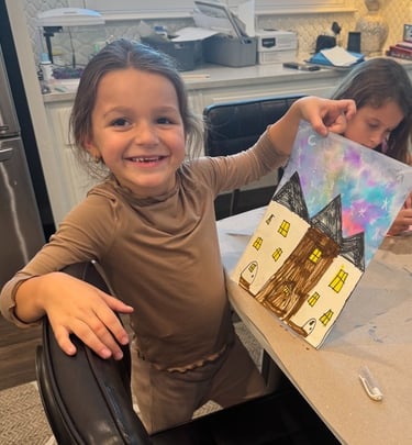 Smiling young artist showing her painted house artwork at Kelley's Neighborhood Art